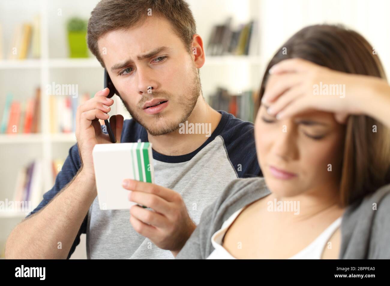 Husband helping his sick wife calling doctor on phone sitting on a