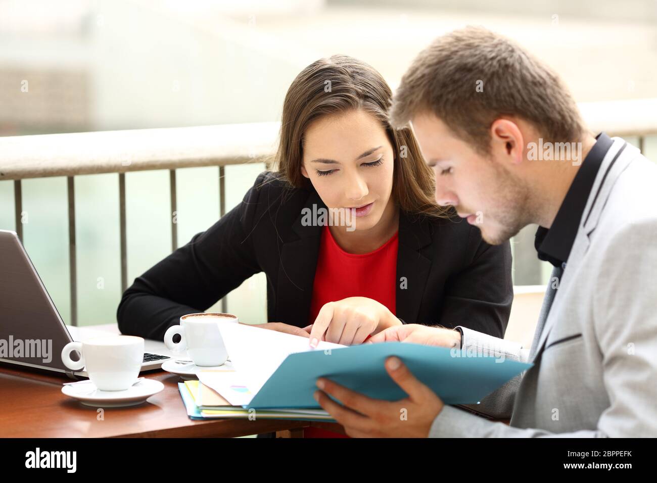 Two executives coworking analyzing documents sitting in a bar Stock Photo