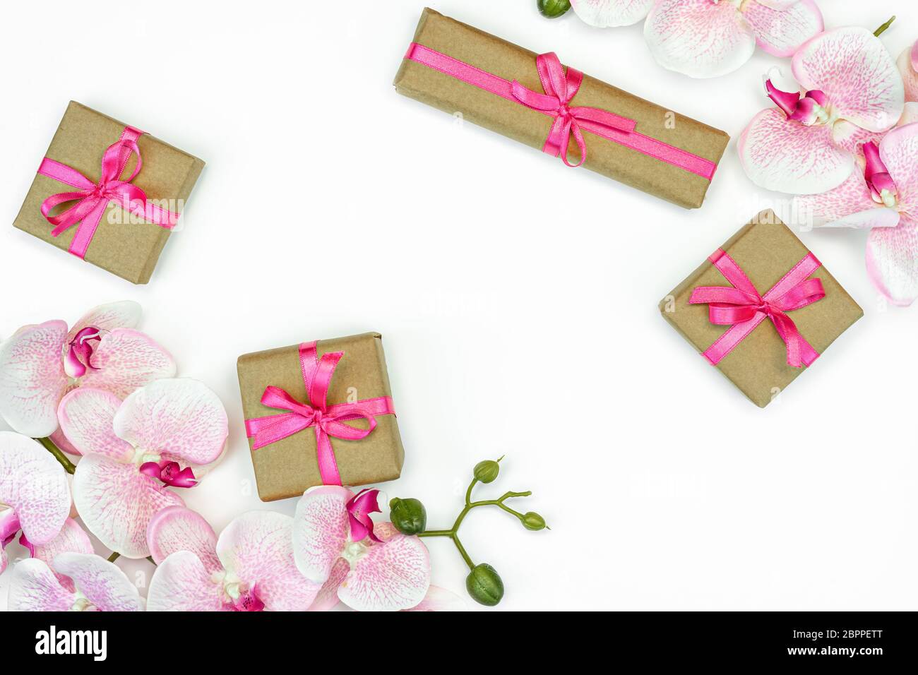 Gift present boxes with pink ribbon, orchid flowers on white background. spring concept. Copy space Stock Photo