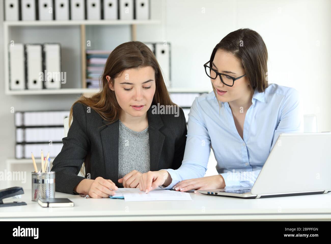 Two concentrated office workers coworking talking about documents on a desktop Stock Photo