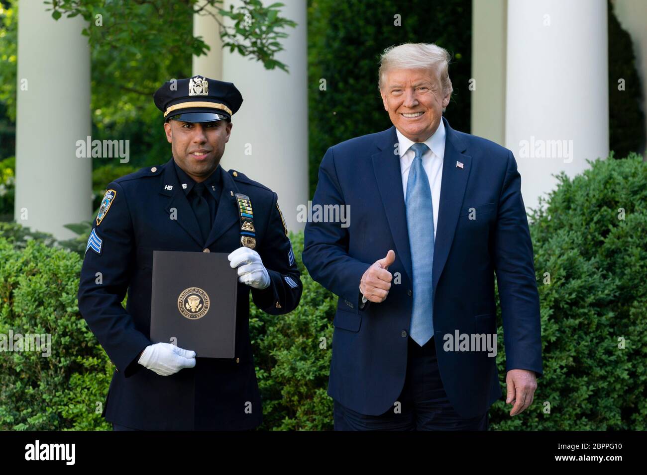 U.S. President Donald Trump presents New York City police officer Spencer Garrett, with a certificate of recognition during the Presidential Recognition Ceremony: Hard Work, Heroism, and Hope in the Rose Garden of the White House May 15, 2020 in Washington, D.C. The event honored front line workers battling the COVID-19, coronavirus pandemic. Stock Photo