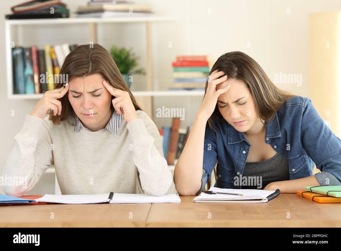 Tired students studying hard memorizing notes preparing exam at home Stock Photo
