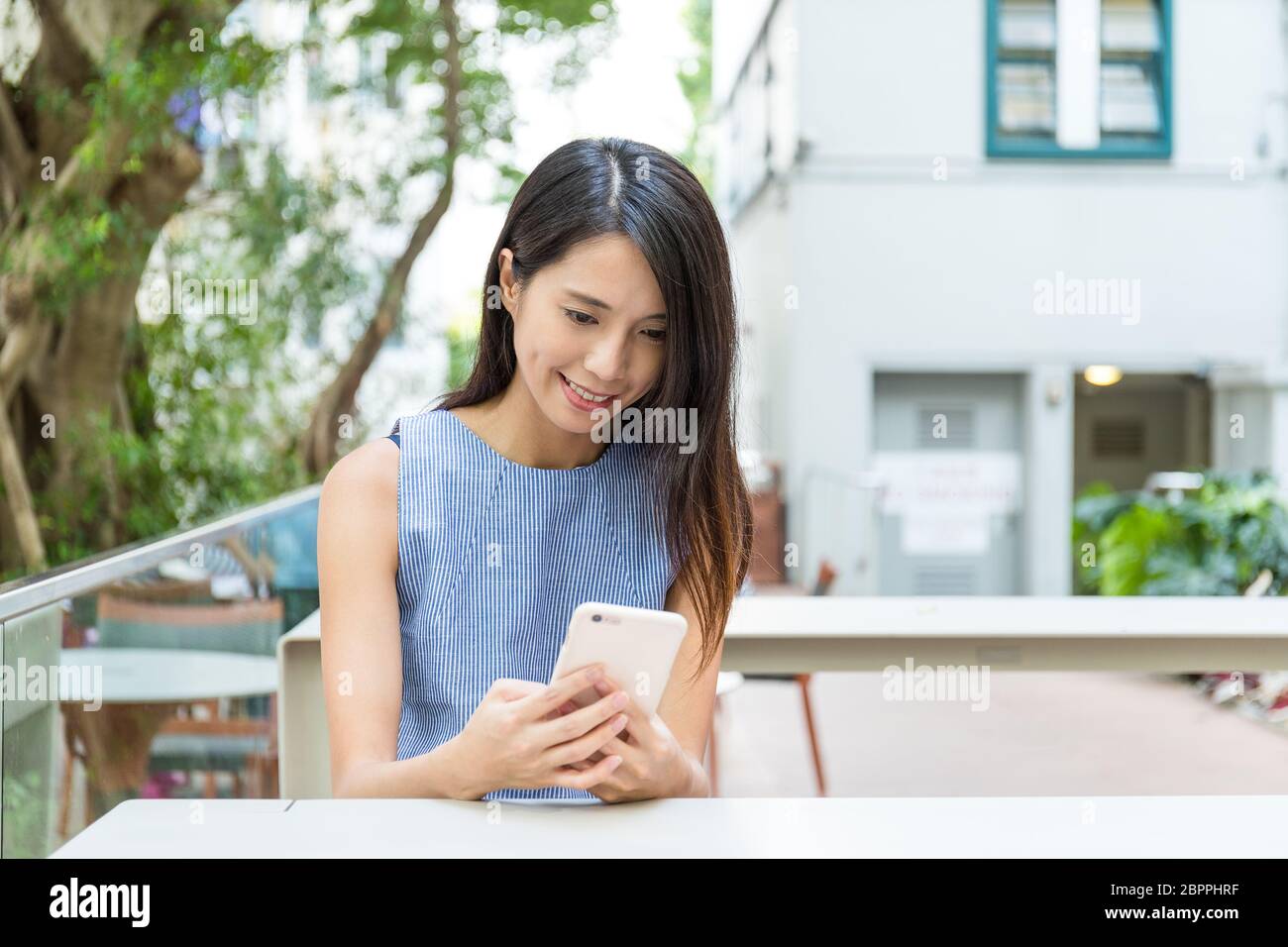 Woman using cellphone in outdoor cafe Stock Photo