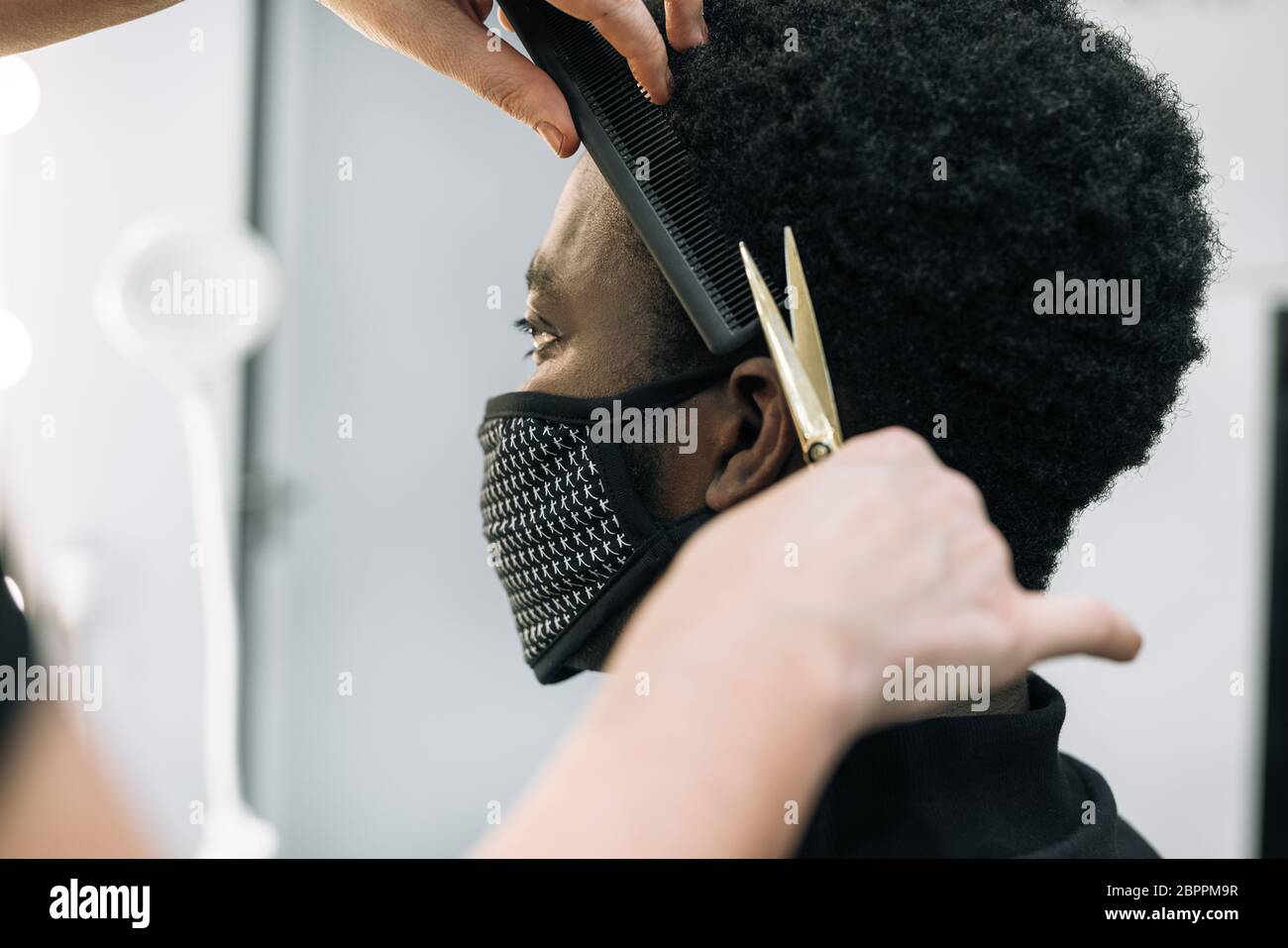 face of a black guy getting a haircut in a hair salon with a black mask