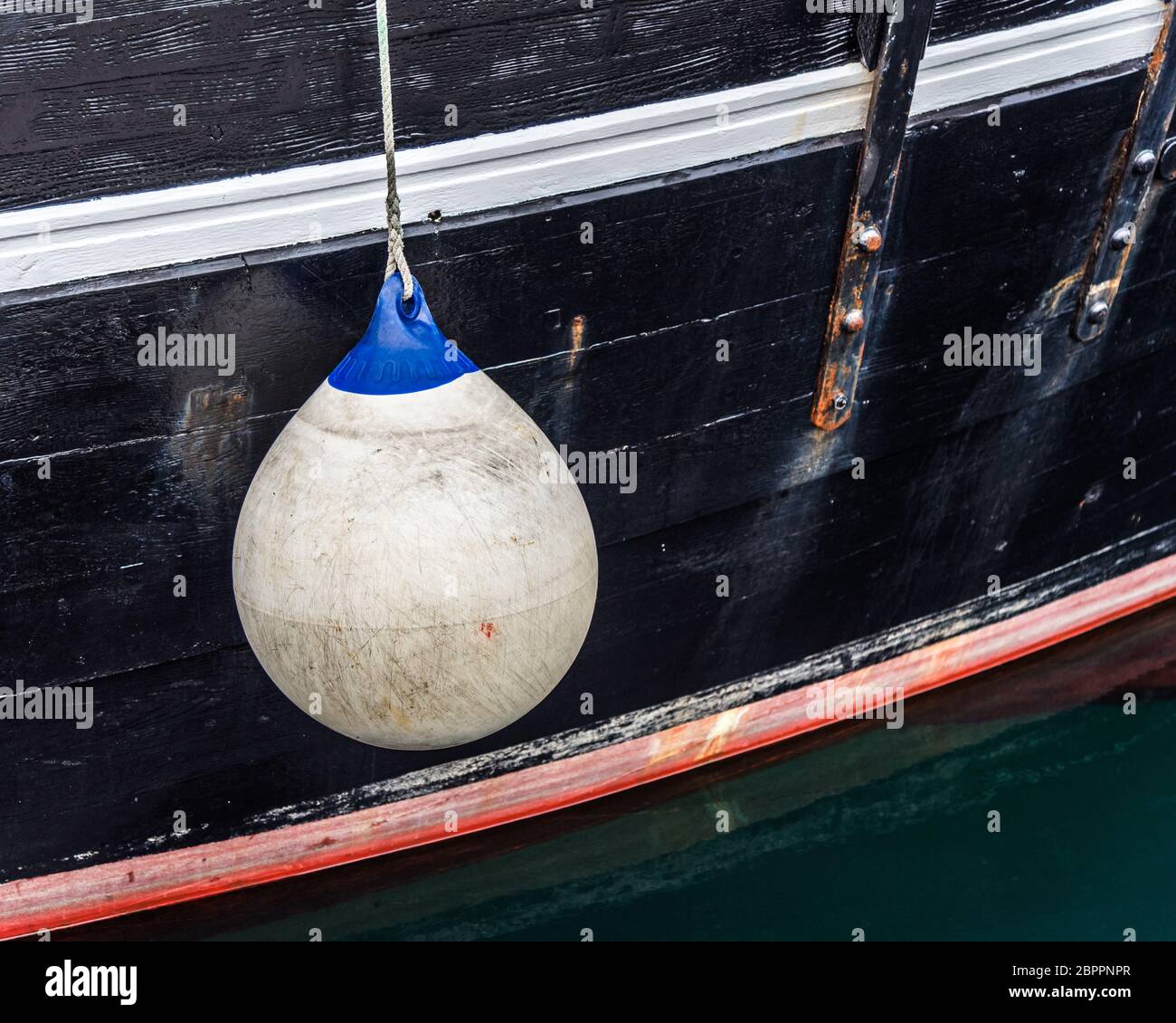 White buoy hanging on a black hull boat Stock Photo
