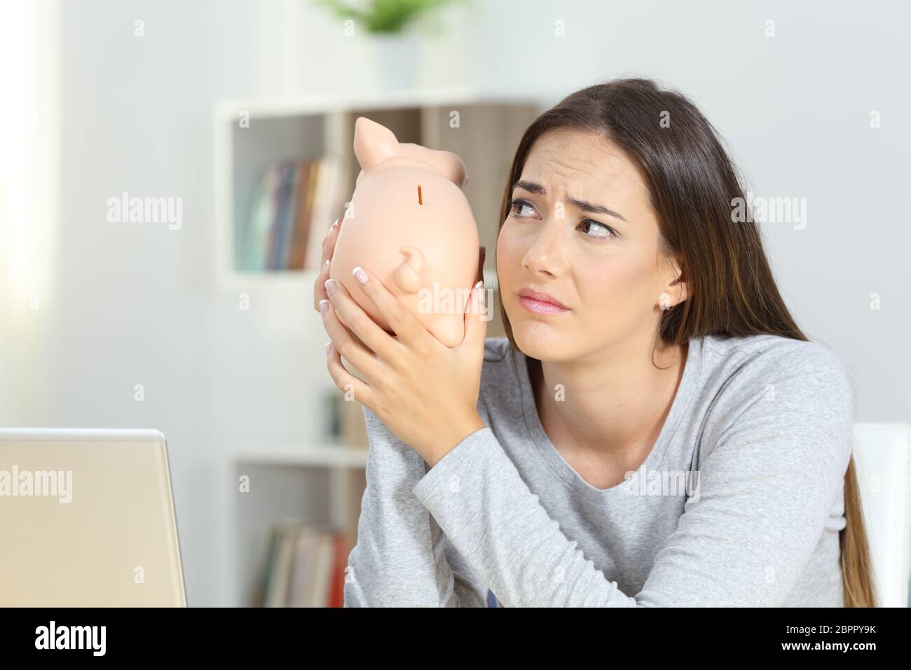 Sad woman shaking a piggy bank at home Stock Photo - Alamy
