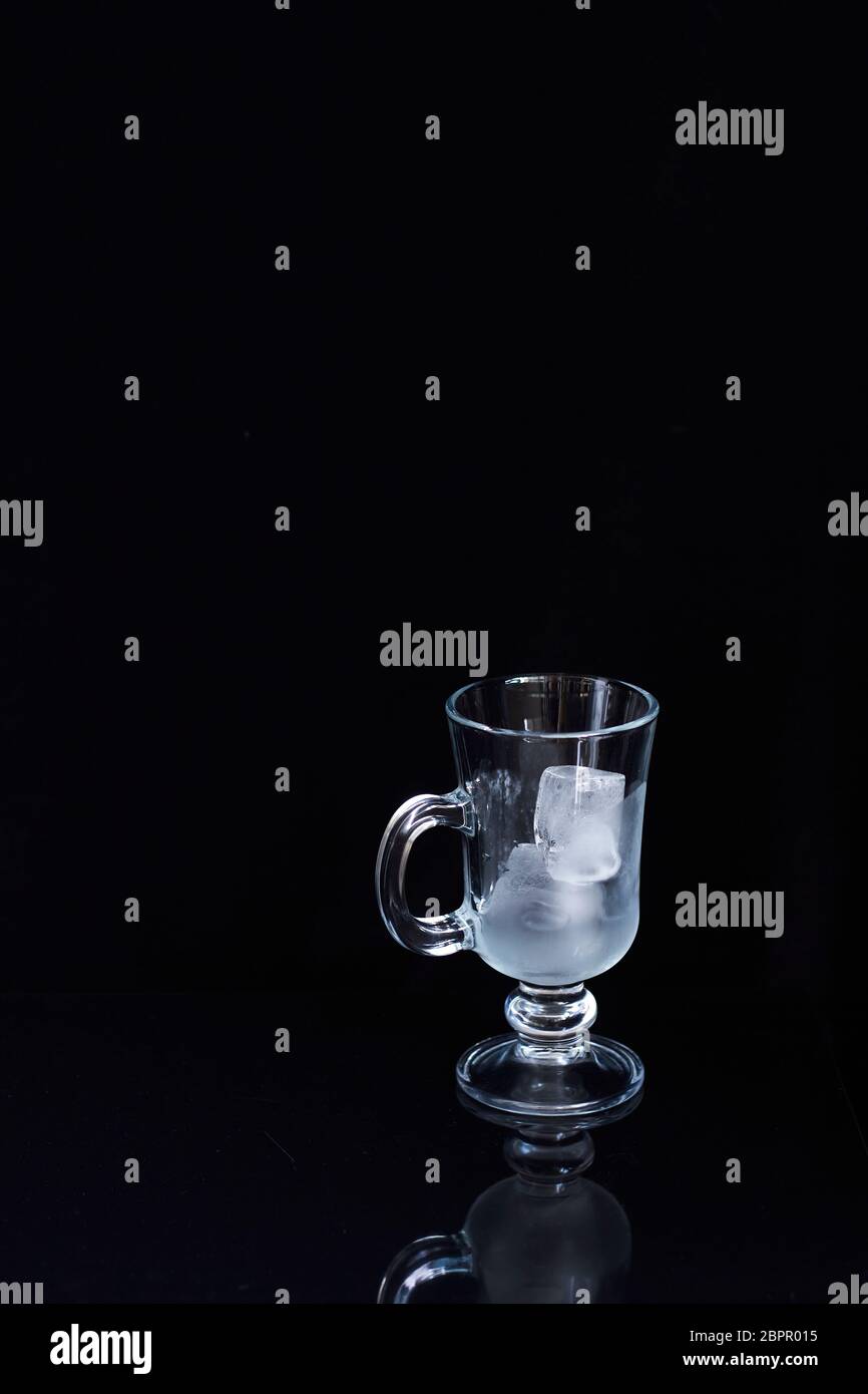 Empty latte glass filled with ice on black background, ice drink concept Stock Photo