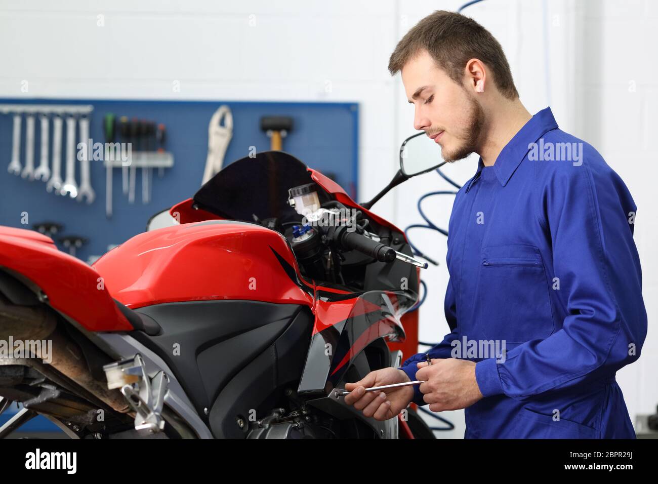 Concentrated motorcycle mechanic working in a mechanical workshop Stock