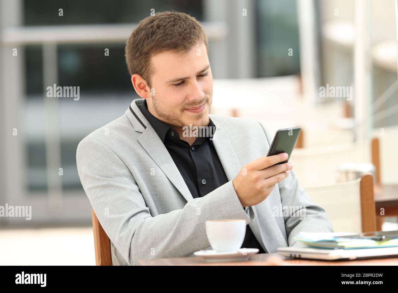 Serious executive using a mobile phone sitting in a coffee shop Stock Photo