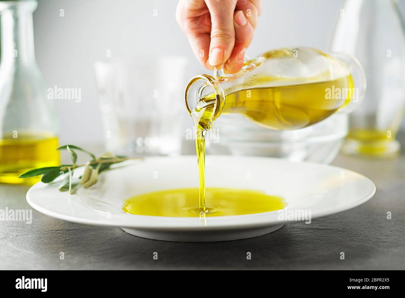 Bottle of healthy virgin olive oil pouring to plate close up Stock Photo