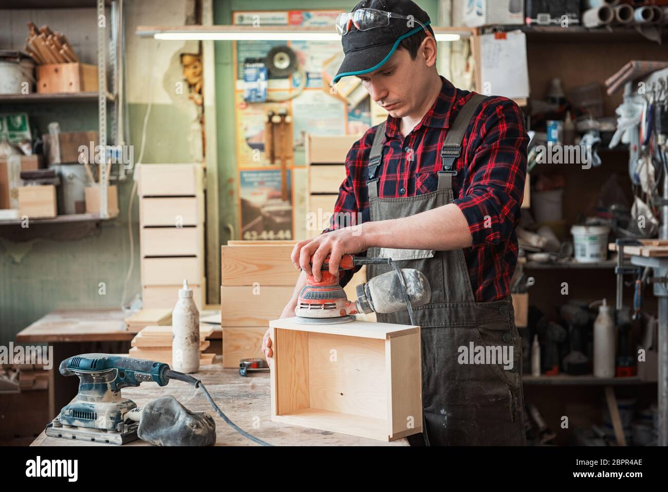 Worker grinds the wood box of angular grinding machine Stock Photo