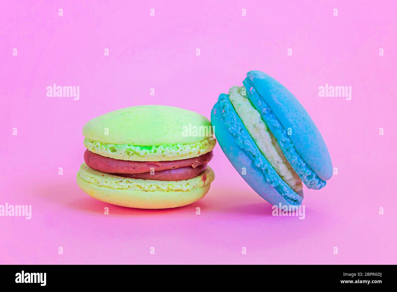 Sweet almond colorful unicorn blue yellow macaron or macaroon dessert cake isolated on trendy pink pastel background. French sweet cookie. Minimal foo Stock Photo
