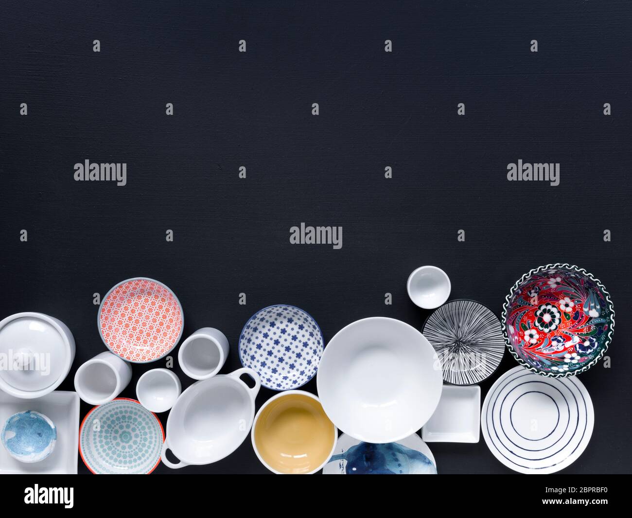 Tableware Background white and coloured tableware in different designs on a black background ...
