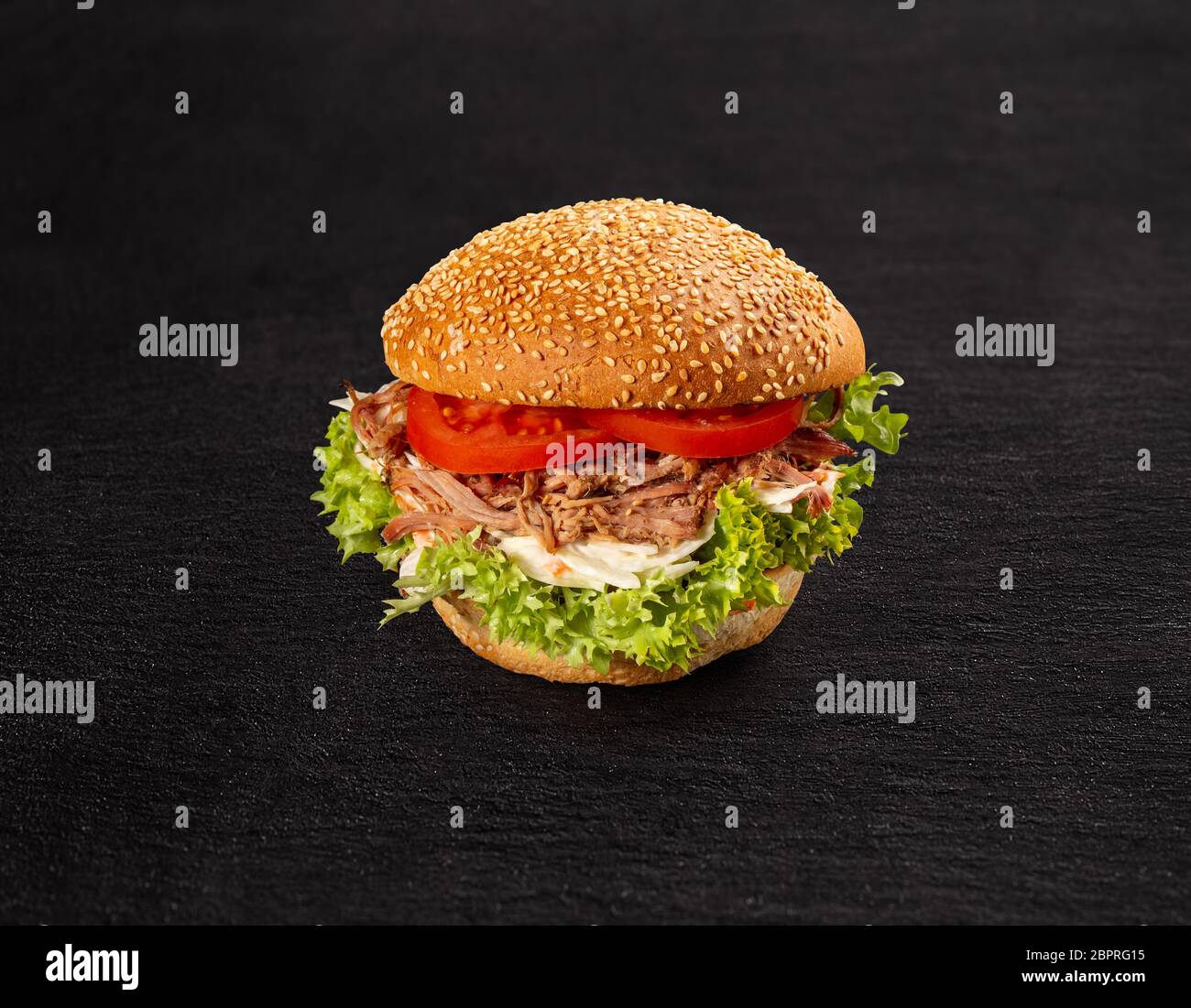 Pulled pork burger with fresh salad and tomato on dark background Stock Photo