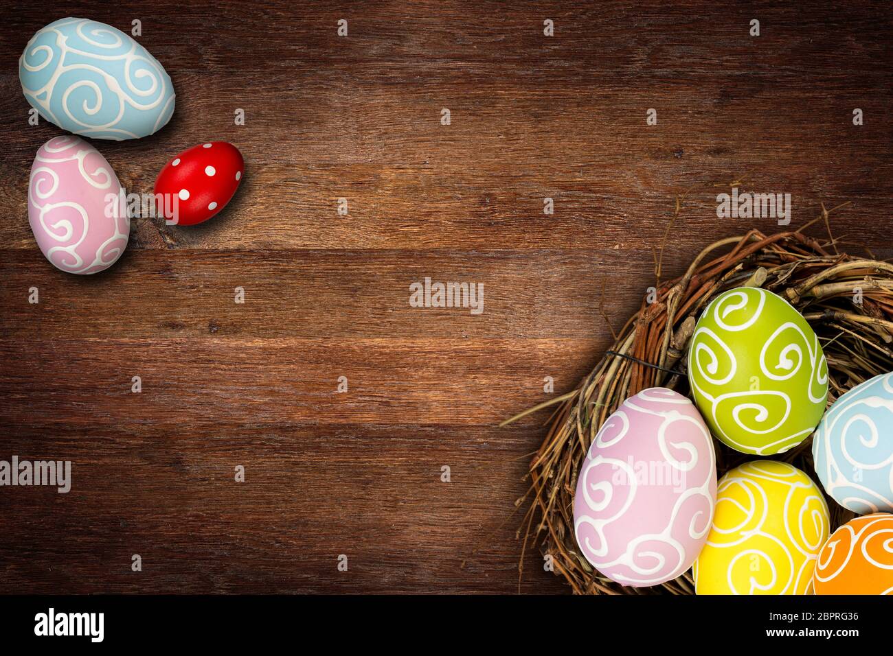 Colorful happy easter eggs in bird nest and tulips on dark empty rustic ...