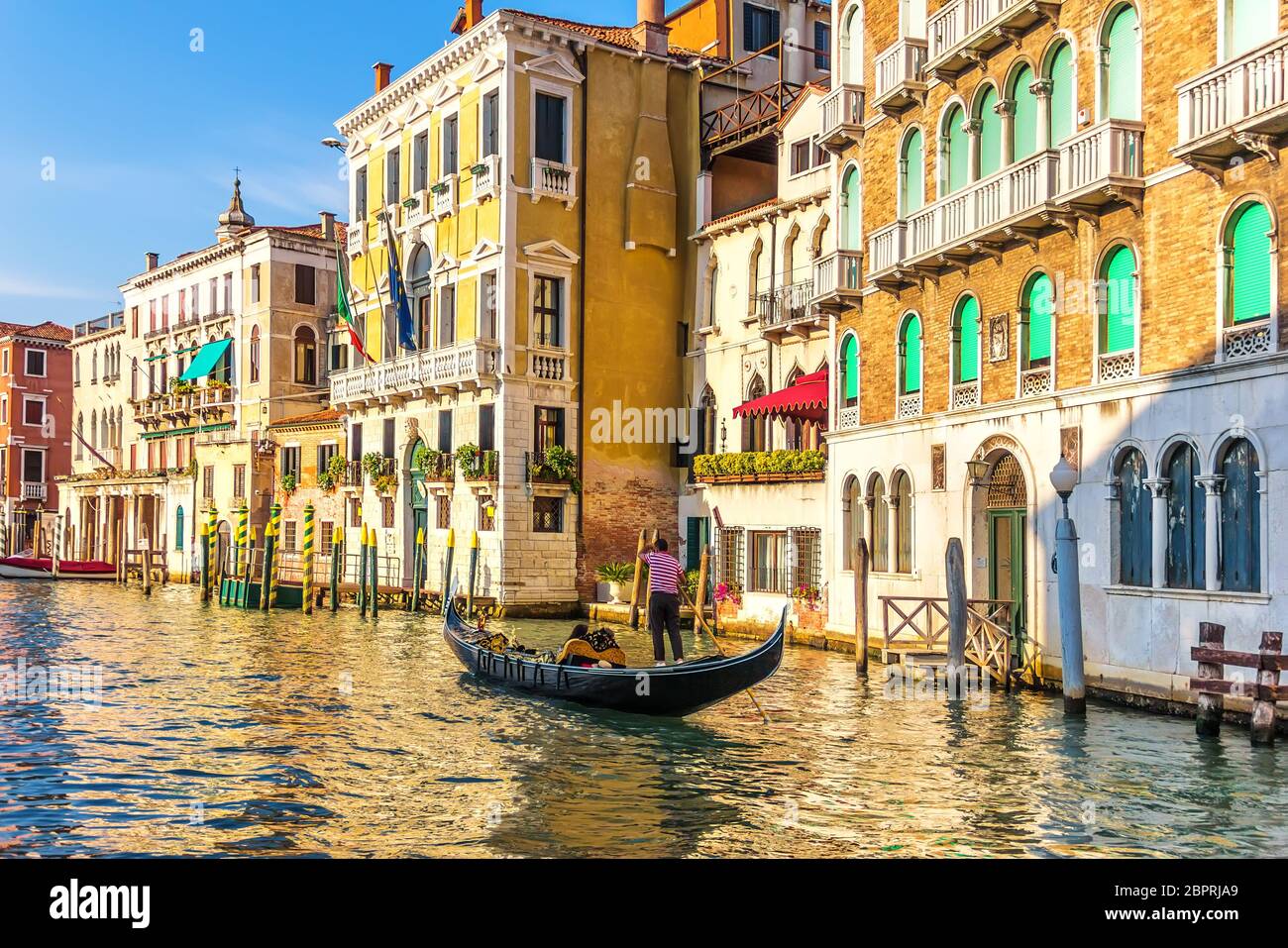 A gondolier in his gondola in the Grand Canal of Venice in front of old palaces. Stock Photo