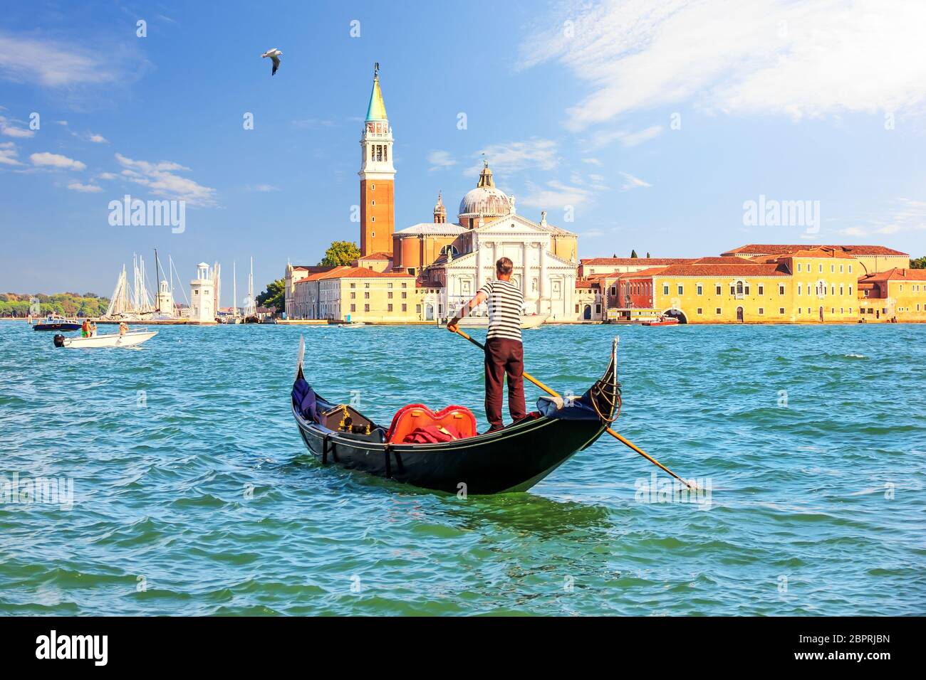 San Giorgio Maggiore Island of Venice and a traditional gondolier in his gondola. Stock Photo
