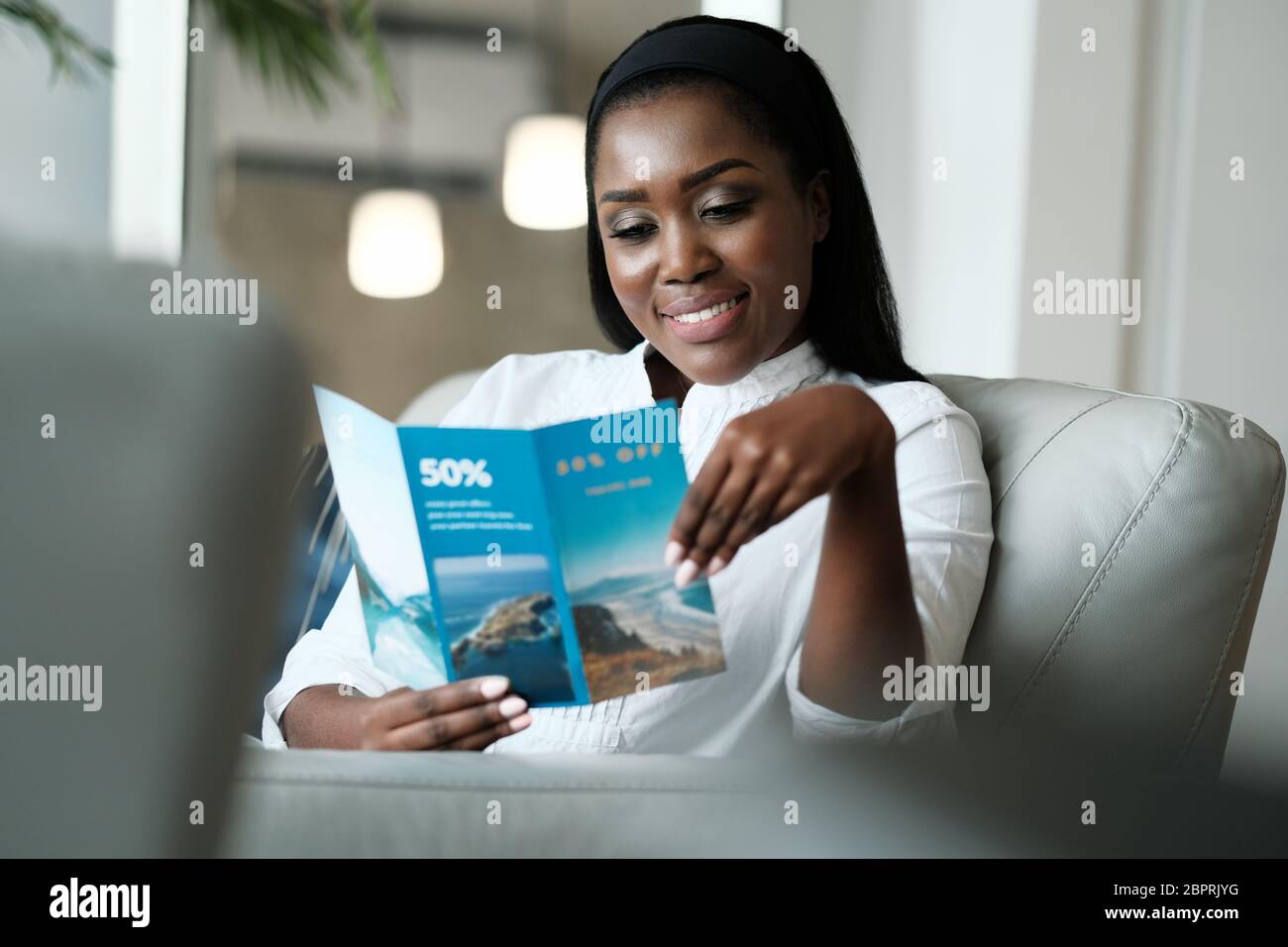 Black Woman Reading Travel Flyer For Holiday Trip Stock Photo