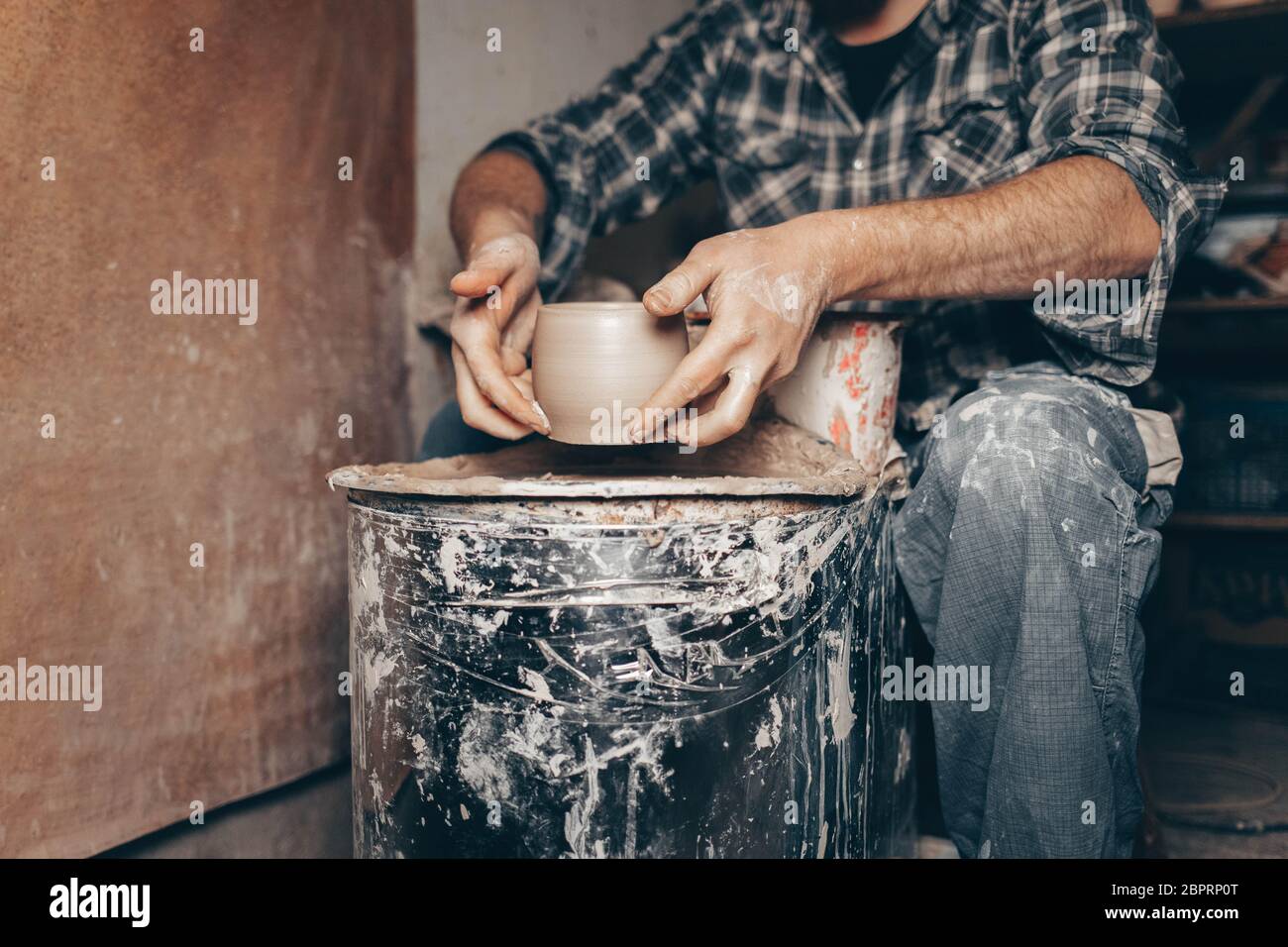 Pottery master works on pottery wheel in workshop Stock Photo