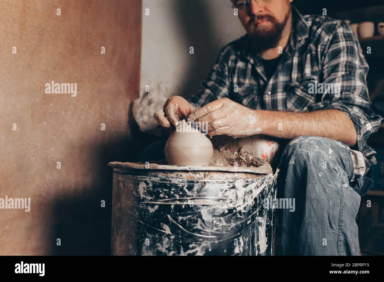 Pottery master works on pottery wheel in workshop Stock Photo