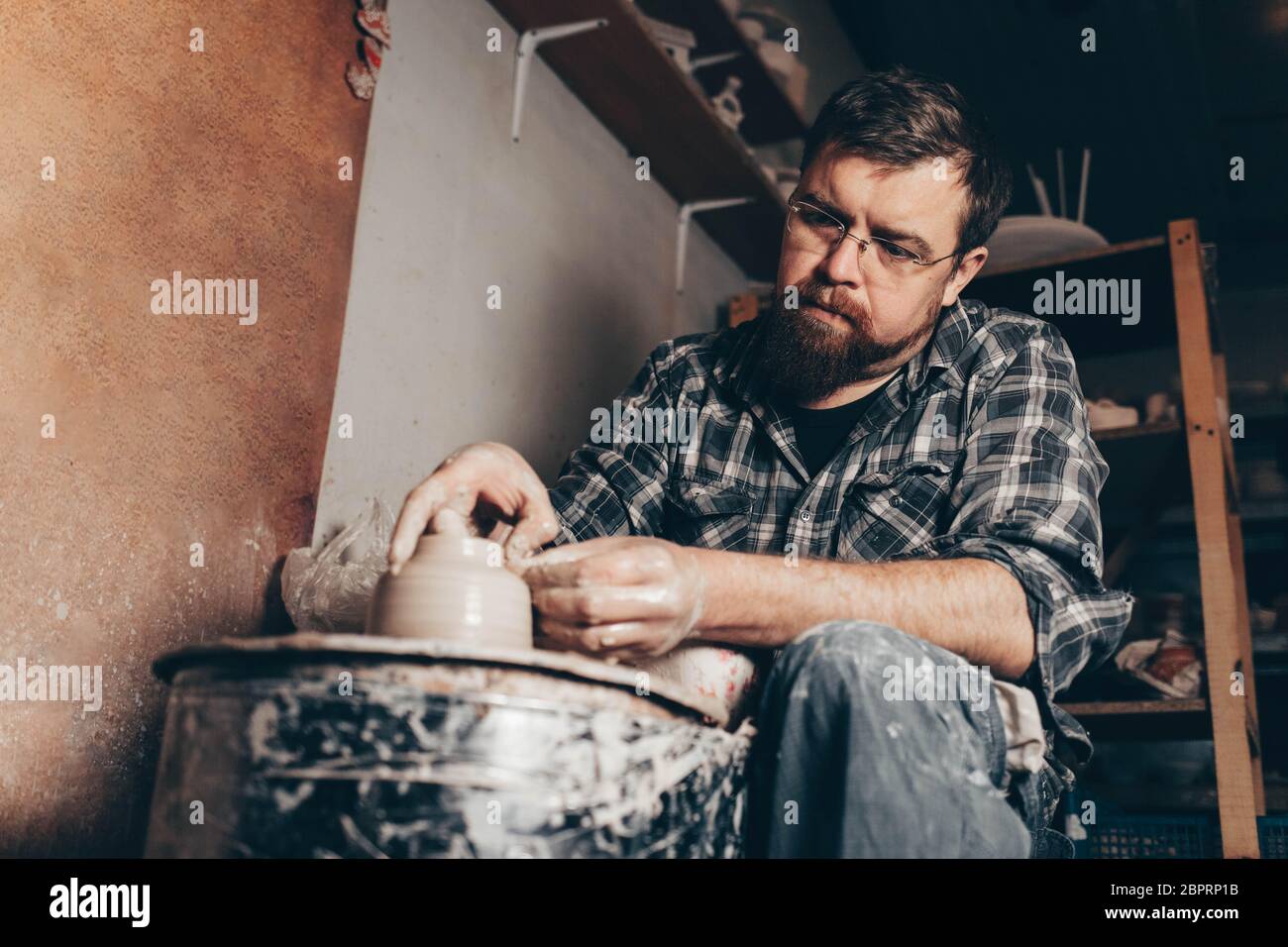 Man works on the potter's wheel creating a jug of clay Stock Photo - Alamy