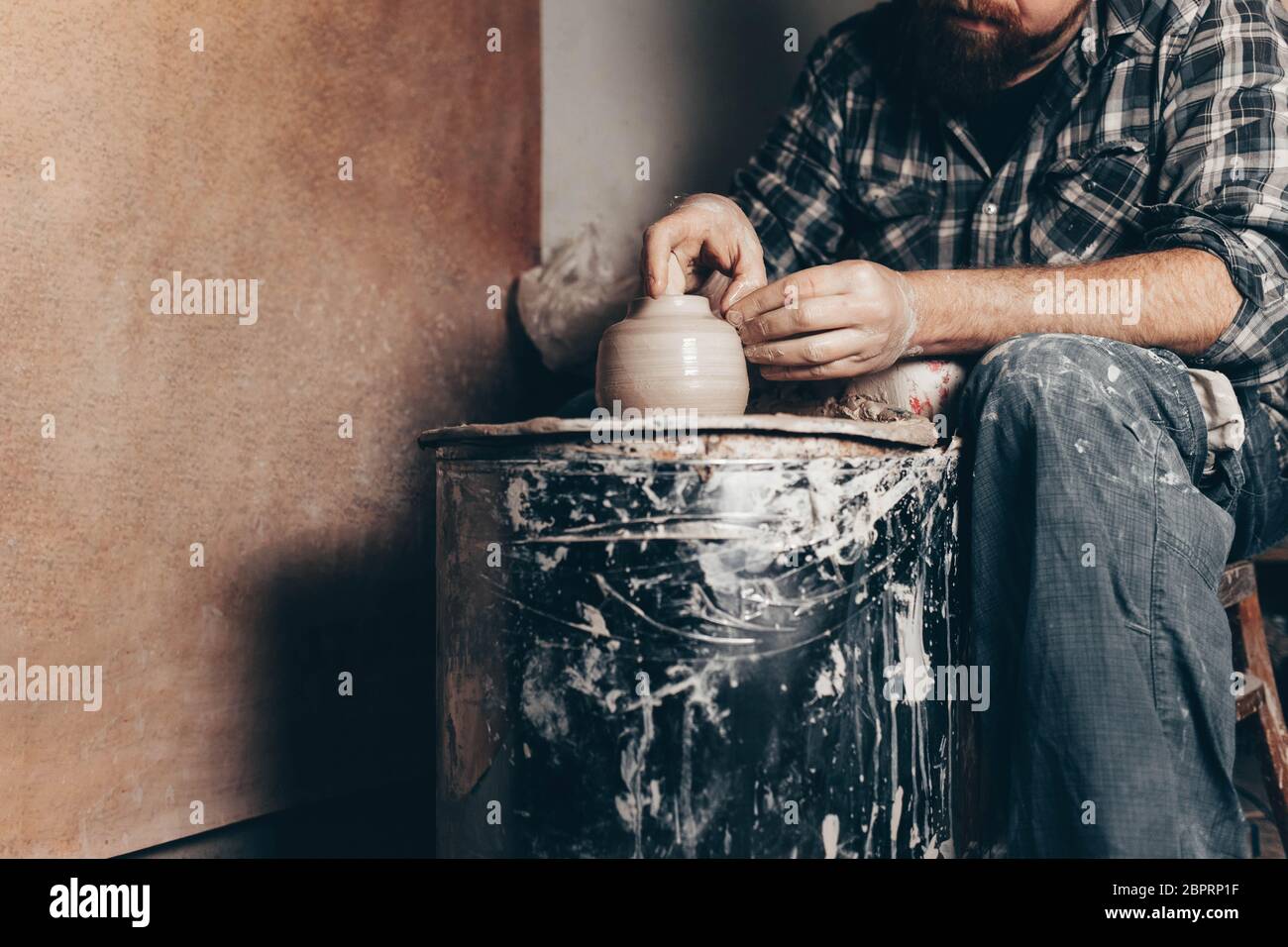 Man works on the potter's wheel creating a jug of clay Stock Photo - Alamy