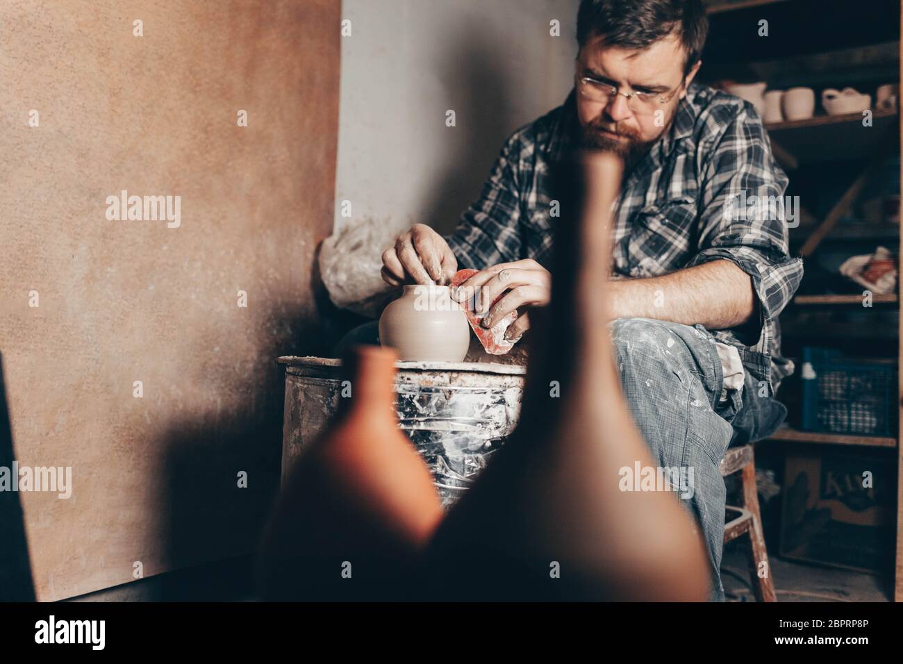 Pottery master works on pottery wheel in workshop Stock Photo