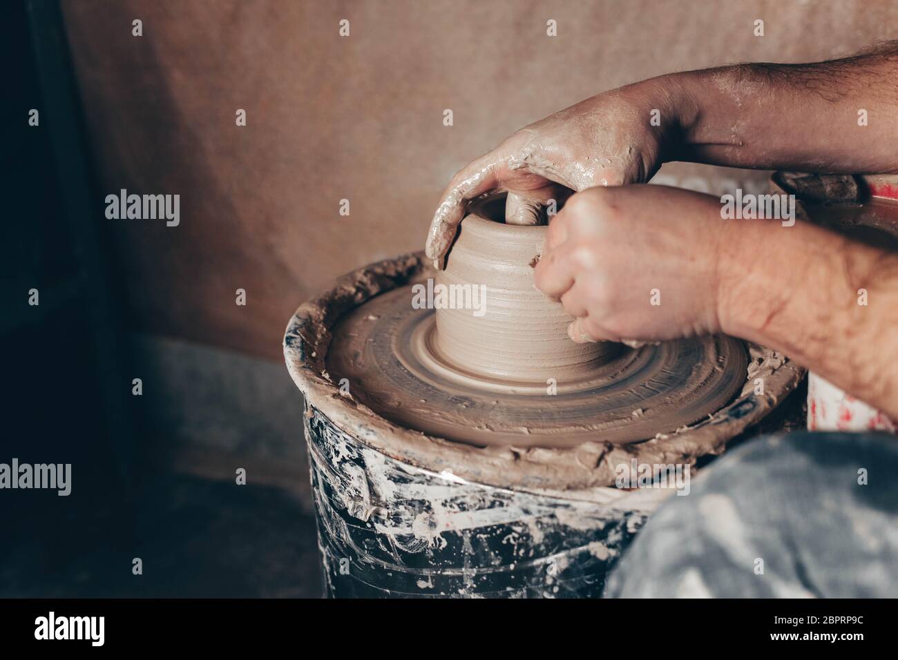 Man forms a white clay product on a pottery wheel Stock Photo