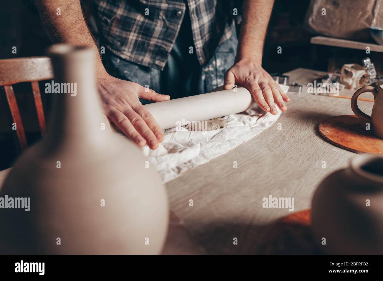 Potter rolls clay. Process of creating a cup of clay products in a pottery workshop Stock Photo