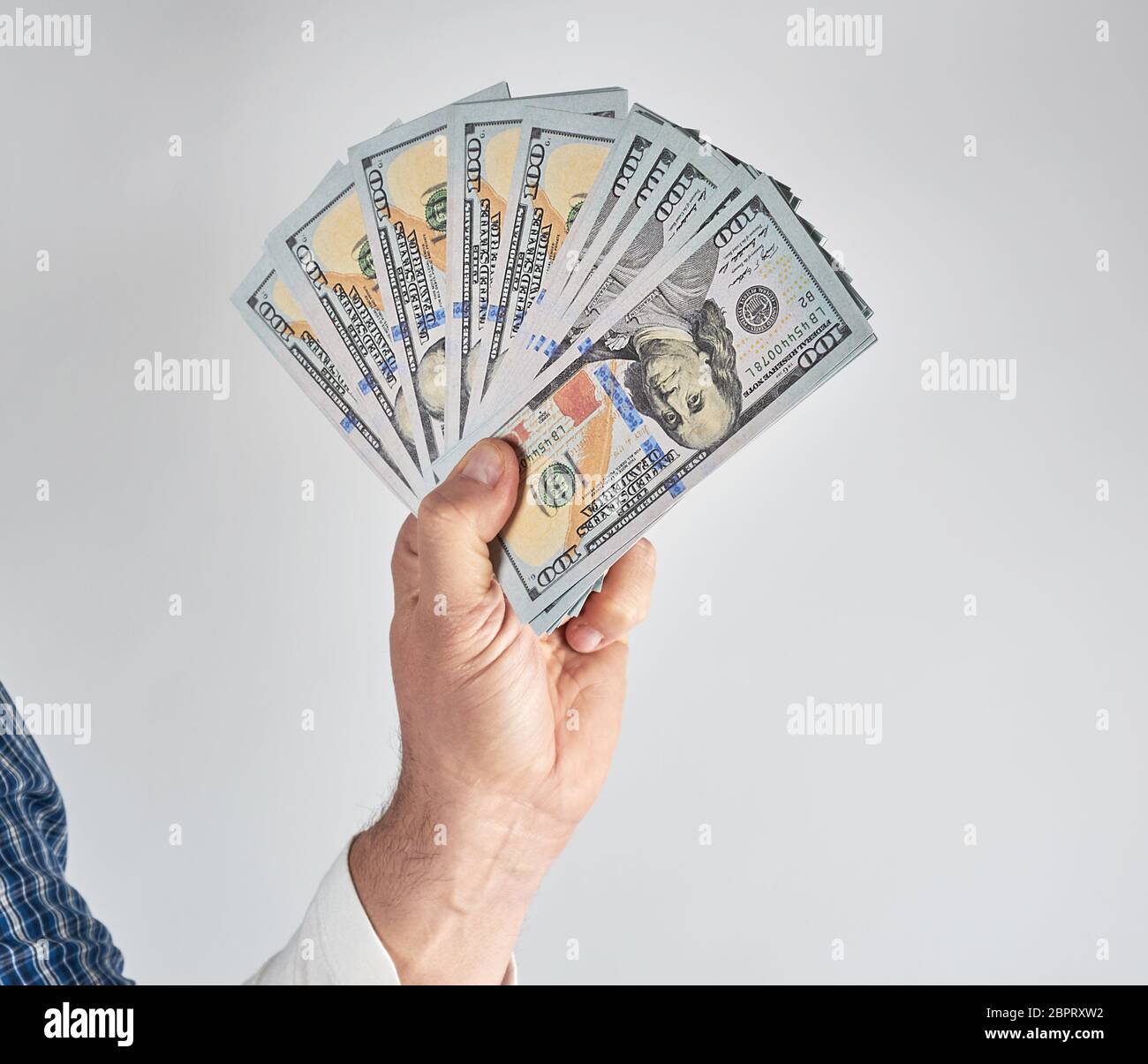 male hand holding a stack of one hundred dollar bills on a white background Stock Photo