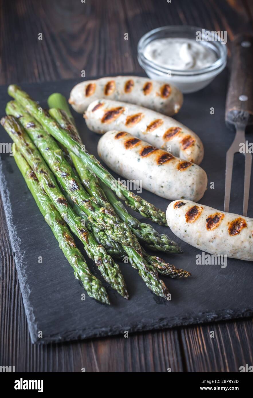 Grilled sausages with asparagus and creamy garlic sauce Stock Photo