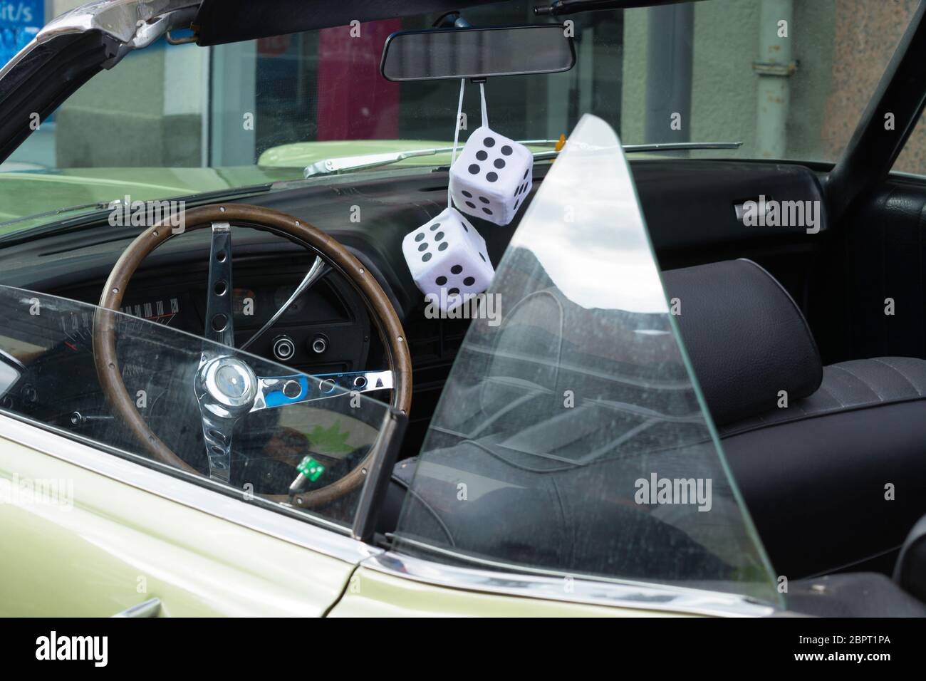 Fuzzy dice hang from the rear-view mirror of a vintage 'low rider