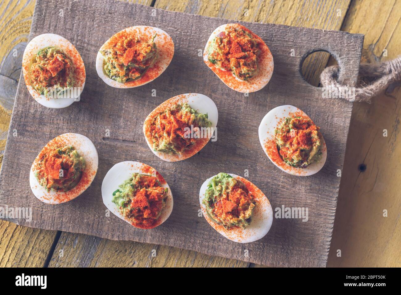 Guacamole and bacon deviled eggs on cutting board Stock Photo