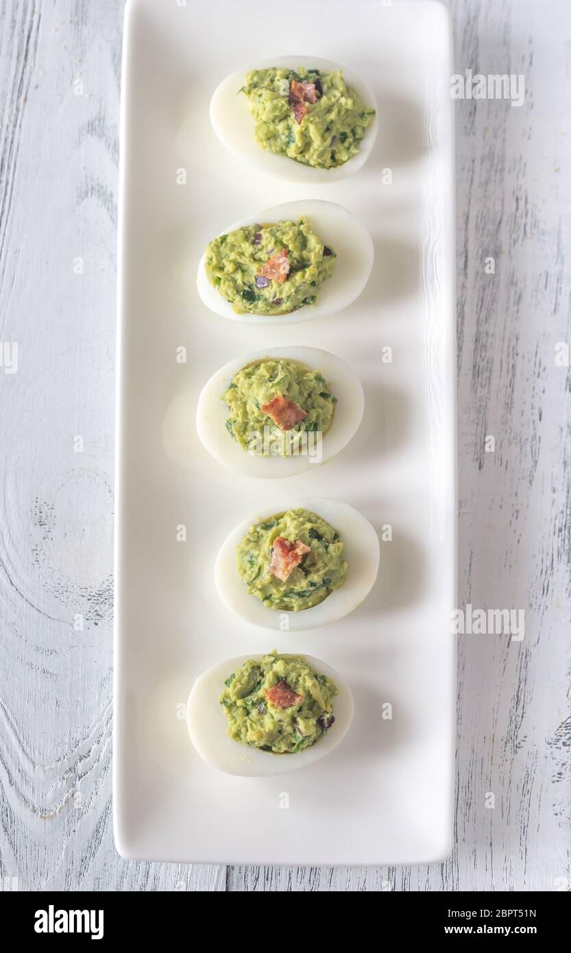 Guacamole and bacon deviled eggs on the white plate Stock Photo