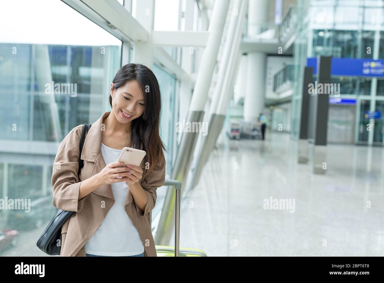 Woman checking on cellphone at Hong Kong airport Stock Photo - Alamy