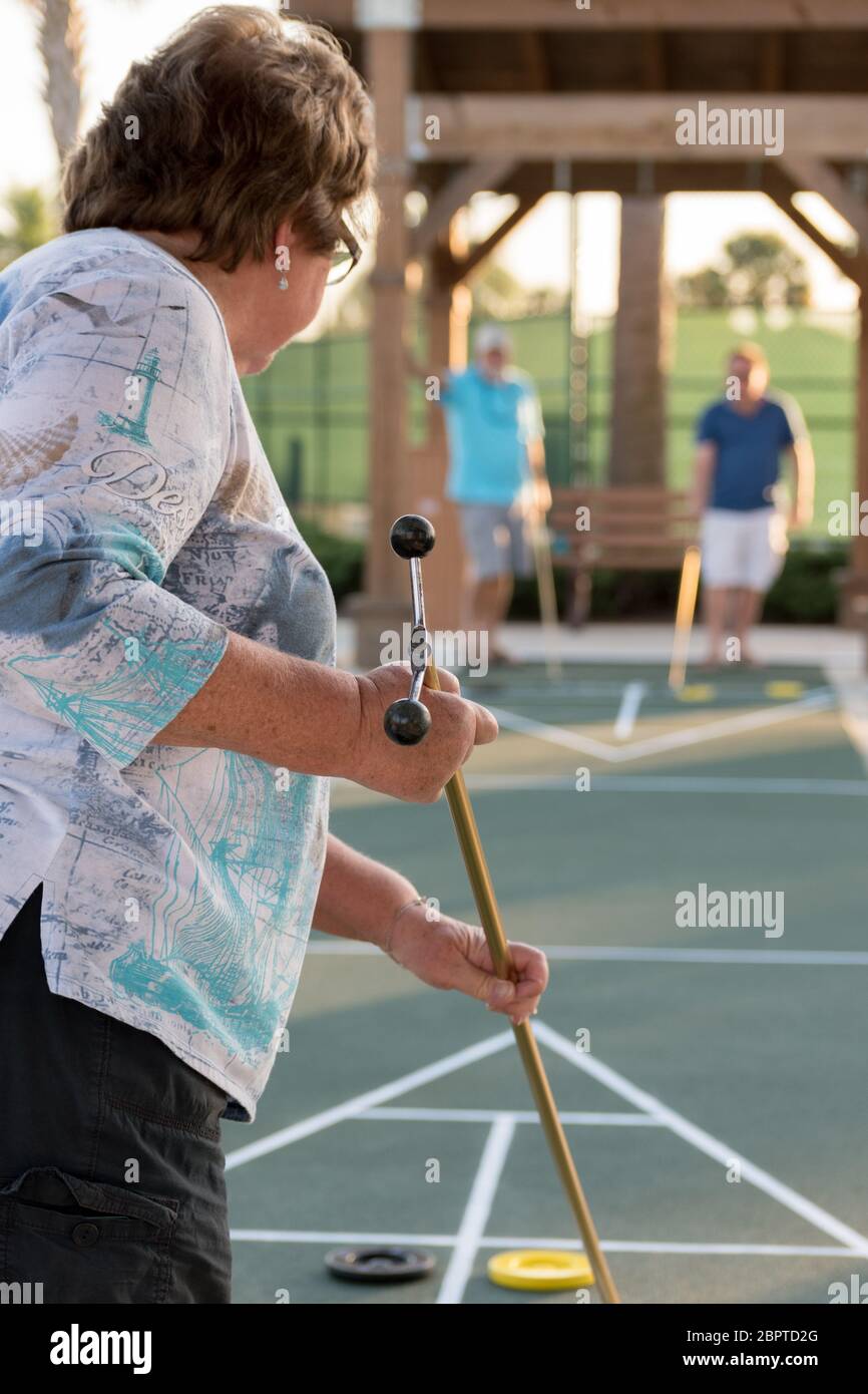 A woman playing a game of shuffleboard with her husband and son Stock Photo