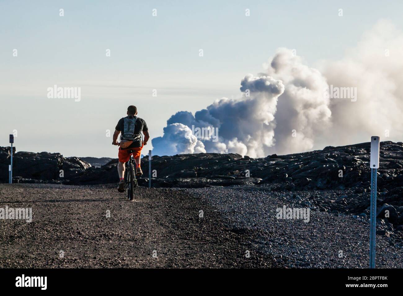 A bicyclist riding the Chain of Craters road out to the lava entry point into the ocean, Puna, Hawaii, USA. Stock Photo