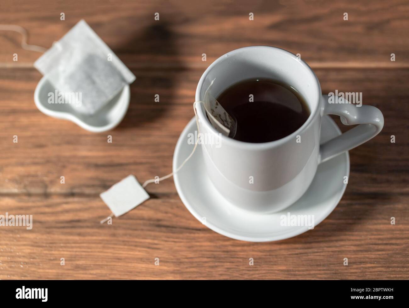 Chinese hot black tea with ceramic mugs with tea bag on a wooden table Stock Photo