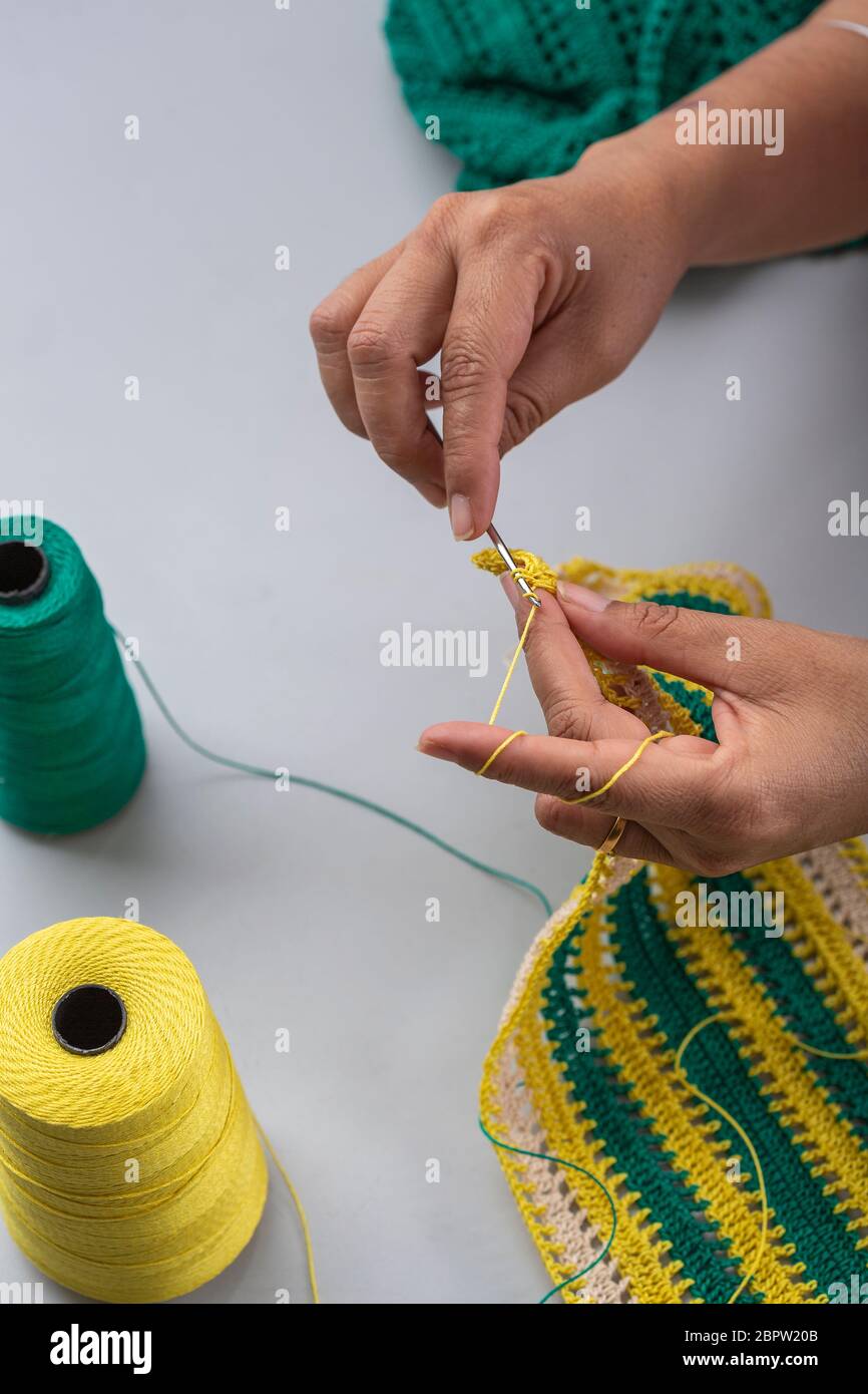 a woman making a thread pattern with yellow and green threads using crochet  hook Stock Photo - Alamy