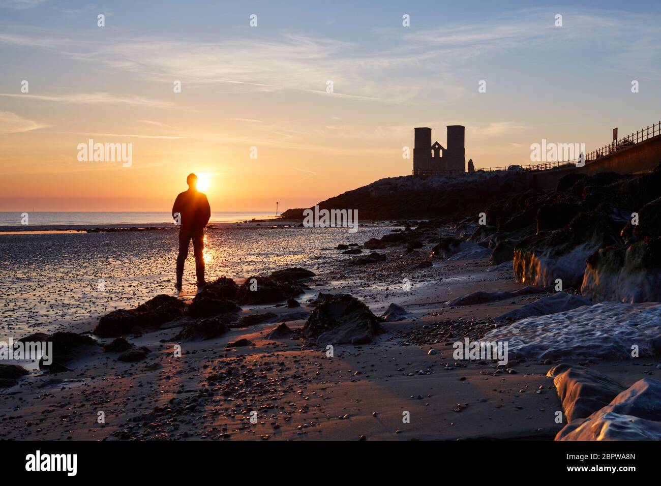 Reculver, Kent, UK. 20th May 2020: UK Weather. A man watches sunrise at Reculver Towers as the tide recedes on what is forecast to be one of the hottest days of the year so far. Credit: Alan Payton/Alamy Live News Stock Photo