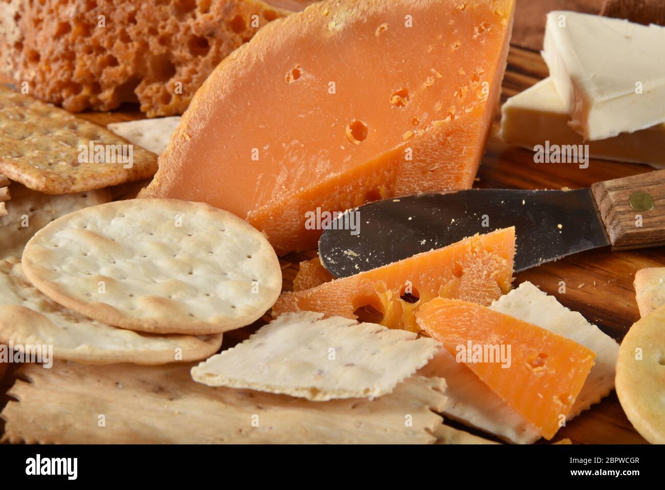 Wedges of gourmet Mimolette cheese with crackers and a cheese knife Stock Photo