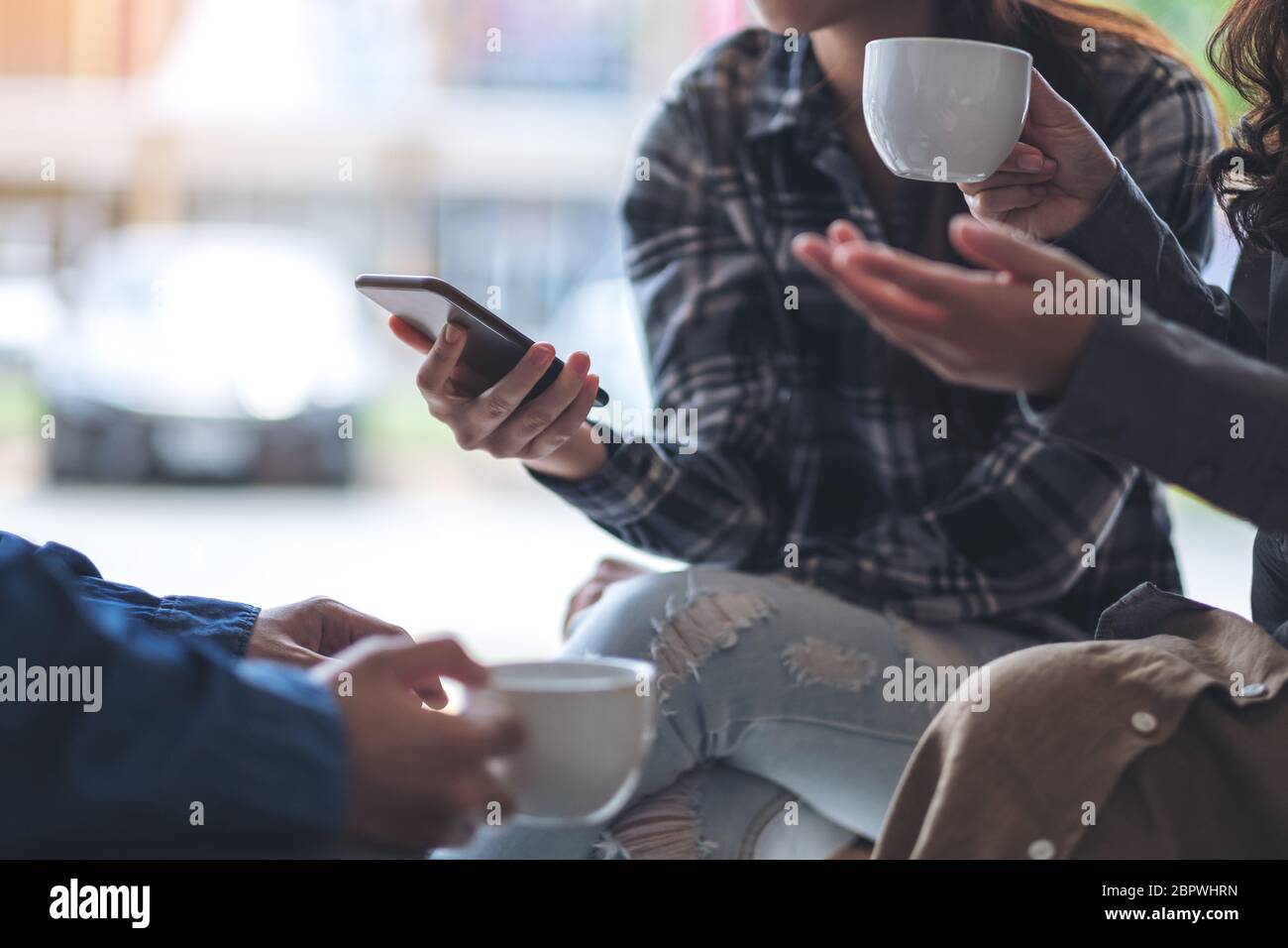 People using phone, talking and drinking coffee together Stock Photo