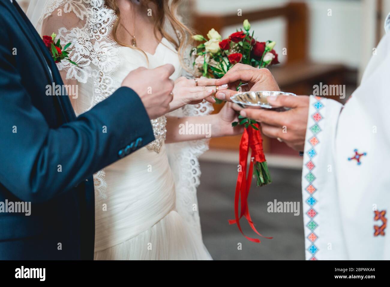 exchanging wedding rings. priest putting on golden wedding rings on fingers bride and groom in