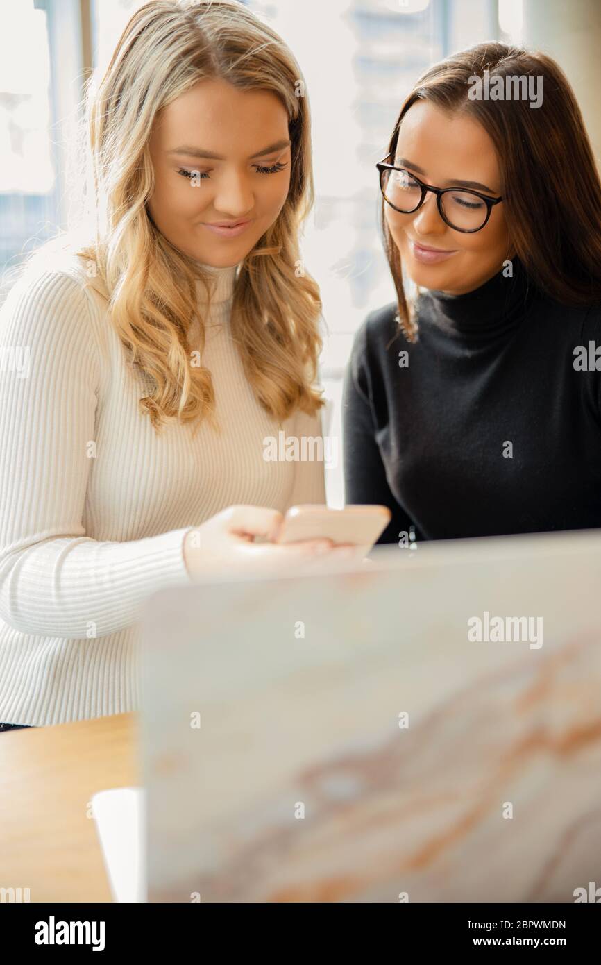 Close-up of School Mates Discussing School Project On Laptop At Cafe Stock Photo