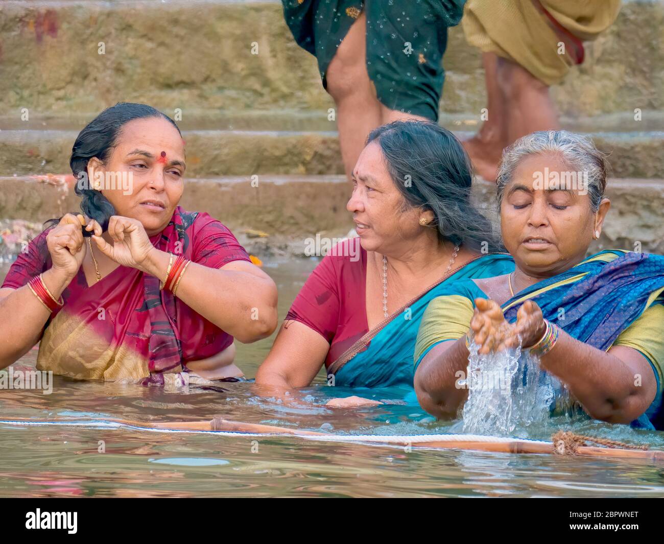 Varanasi, India - Nov 14, 2015. Three Indian women bathe in the Ganges River, on a Hindu religious pilgrimage during the annual Diwali Festival. Stock Photo