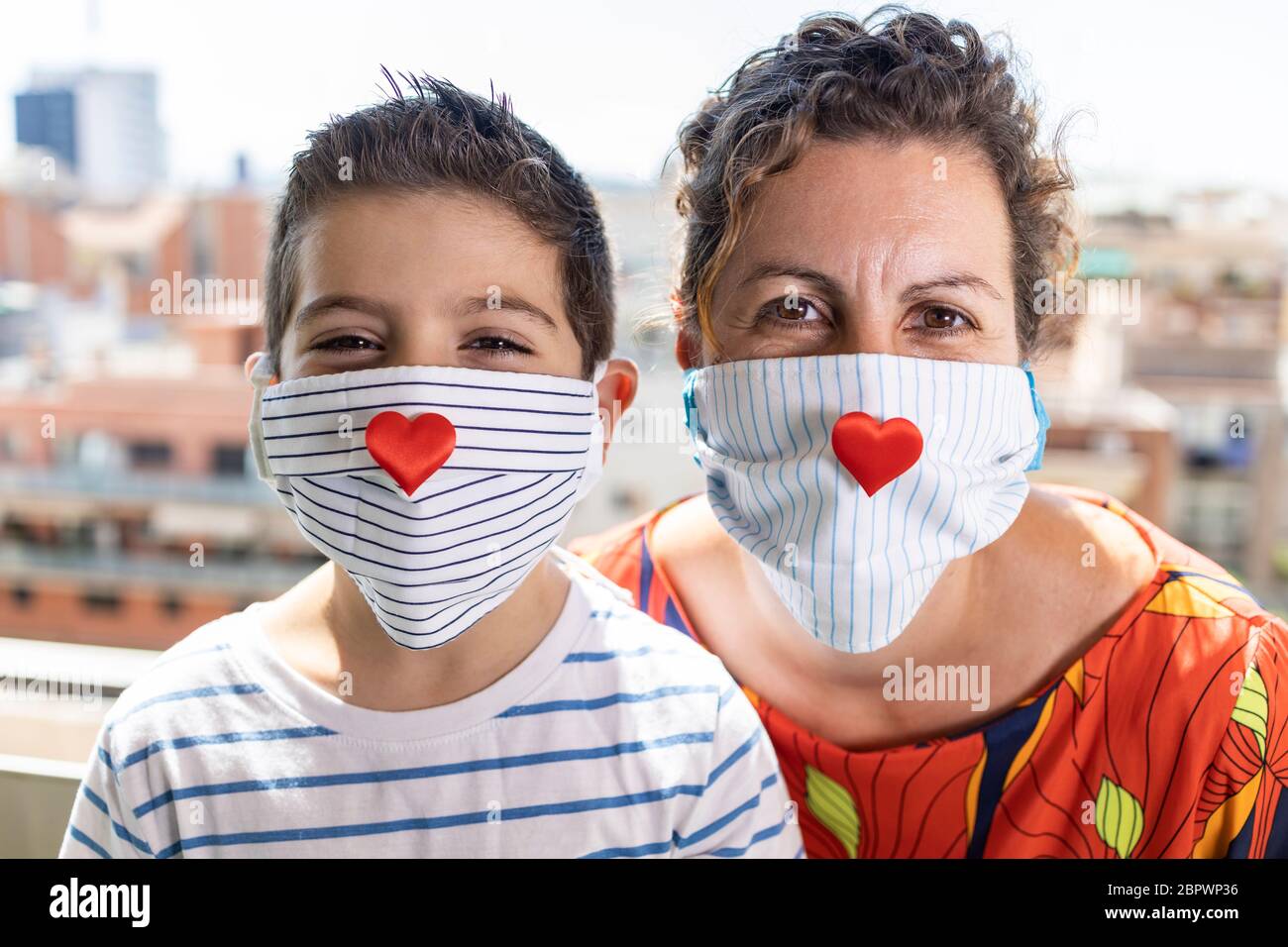 Mother and son with hearts in their face masks Stock Photo - Alamy