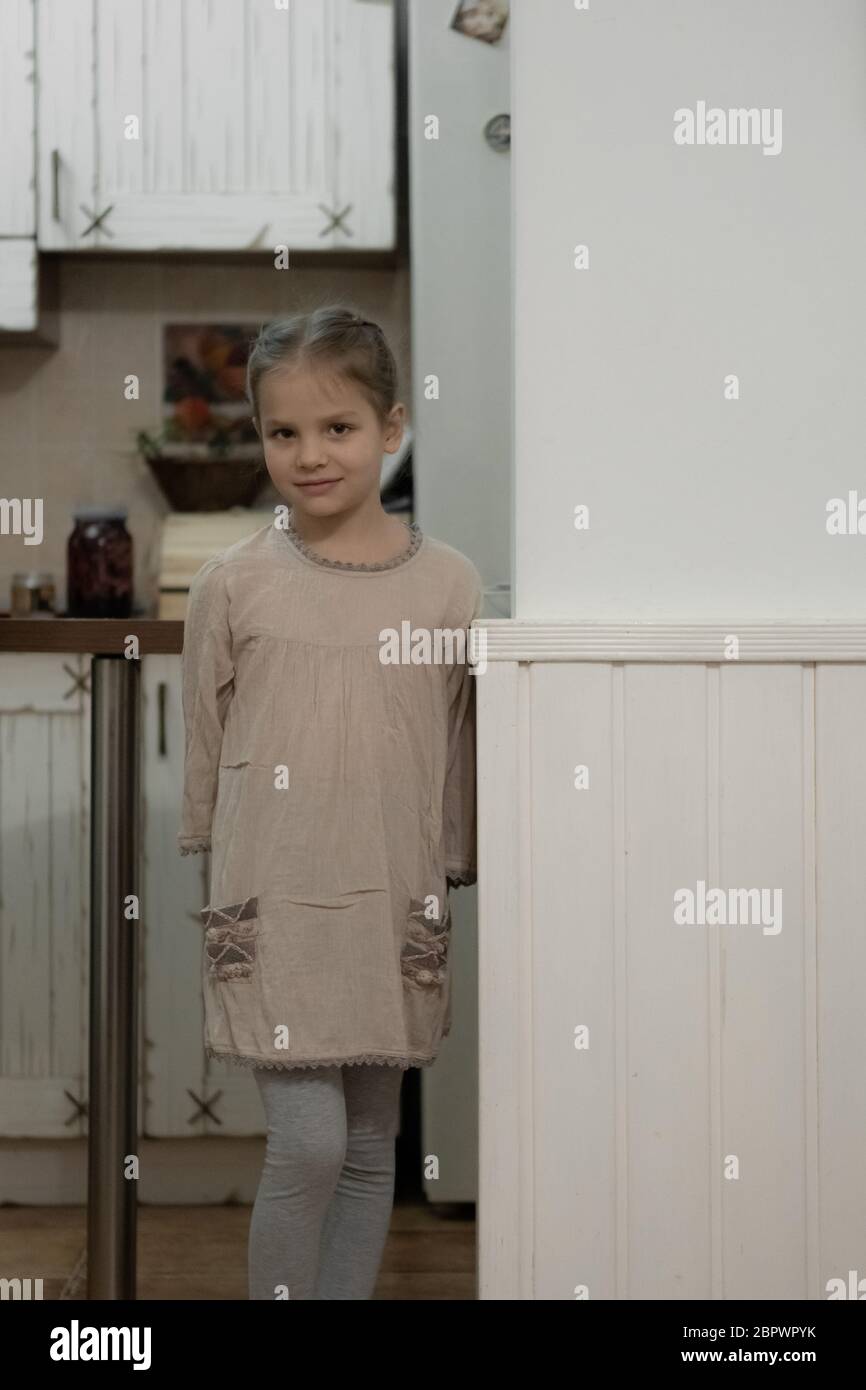 Dark blonde girl in a beige dress in the middle of the kitchen. Stock Photo