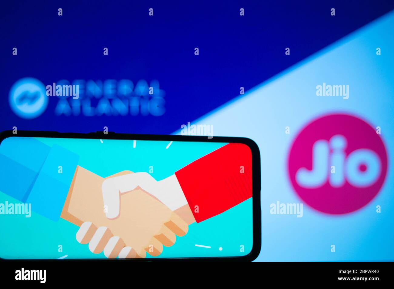 Jaipur, India, Circa 2020 - Photograph of a mobile phone with a handshake, signifying a deal, with general atlantic and Reliance jio in the background Stock Photo