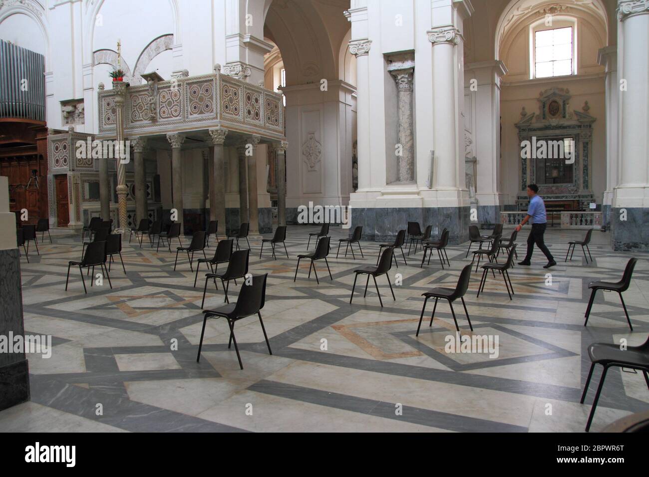 An employee of the Cathedral has in the central nave the chairs for the faithful respecting the rules on the distance between people Stock Photo
