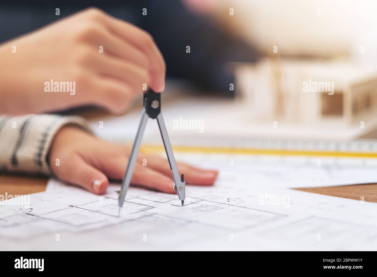 An architect using compass to draw and measure shop drawing in office Stock Photo